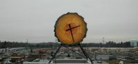 Federal Way Transit Center clock, in the shape of a cut log, with The Commons At Federal Way mall and other City Center Core retail development in the background.